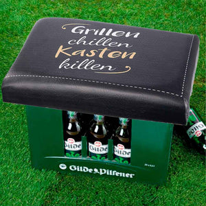 Auf einem Bierkasten ist ein Bierkastensitz mit der Aufschrift: Grillen, chillen, Kasten killen. Geschenkidee für Biertrinker.