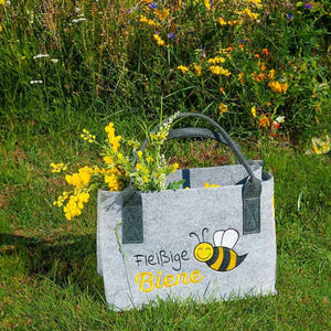Schulterbarer Filzshopper von Gilde mit der Aufschrift fleißige Biene steht in einer Blumenwiese
