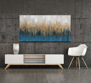 Ein abstarktes Kunstwerk hängt an einer tristen grauen Wand. Die Farben des Acryl-Gemäldes sind Gold und Blau