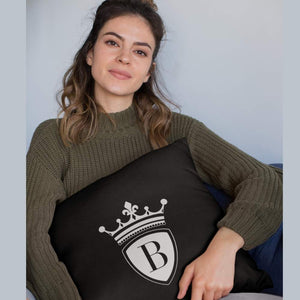 Kissen 40x40cm schwarz mit BRIDEMAKER Logo. Das samtige Kissen liegt auf dem Schoß einer jungen Frau