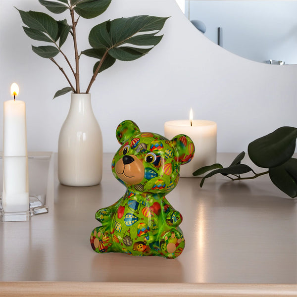 Bär Toto von Pomme Pidou in der Farbe Grün sitzt auf eine Seideboard