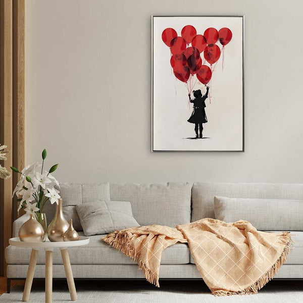 Ein gerahmtes Gemälde hängt im Wohnzimmer über der Couch. Auf dem Gemälde lässt ein Mädchen rote Luftballons steigen.