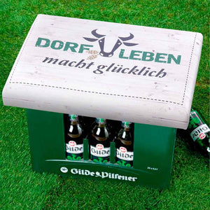Bierkastensitz auf einem Bierkasten mit dem Spruch, Dorfleben macht glücklich. 