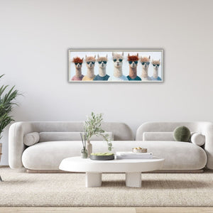 In einem hellen Wohnzimmer steht ein Esstisch und dahinter eine helle Couch. Darüber hängt ein Bild mit sieben Lamas die Frisuren aus Kunstfell haben.