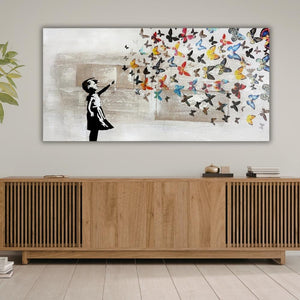 Modernes Street-Art-Gemälde „Vom Loslassen“ auf Leinwand mit einer schwarzen Mädchen-Silhouette, die einen Schwarm farbenfroher Schmetterlinge freilässt, gestaltet mit haptischer Spachteltechnik und Jute-Struktur.