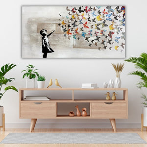 Modernes Leinwandbild „Butterfly Girl“ im urbanen Kunststil als Wanddekoration über einer TV-Kommode aus hellem Holz mit skandinavischer Deko und Teppich.