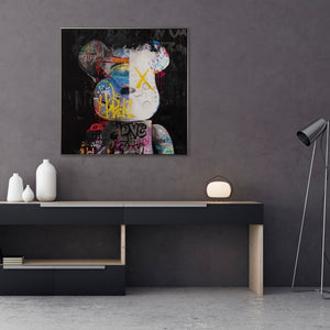 Ein Sideboard steht in einem Büro. An der dunkelgrauen Wand hängt ein Bild Auf ihm ist ein Teddybär auf schwarzem Hintergrund zu sehen. Auf dem Teddy sind unterschiedliche farbige Schriften im Graffiti Style.