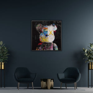An einer grauen eintönigen wand hängt ein gerahmtes farbenfrohes Bild von einem bunten Teddybären.