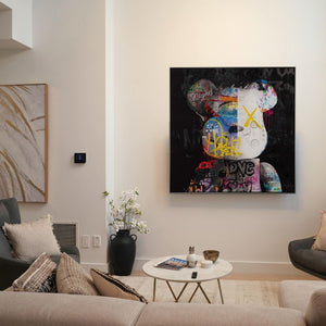 In einem hellen Wohnzimmer hängt ein farbenfrohes Bild von einem Teddy an der Wand. Bunte Graffiti Elemente bringen Farbe auf das dunkle oder düstere Bild.