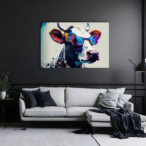 An einer schwarzen Wand steht ein graues Sofa. Darüber hängt ein Bild von einer bunten Kuh im Pop-Art Style. Die Kuh trägt eine Sonnenbrille. Der raum ist modern eingerichtet.