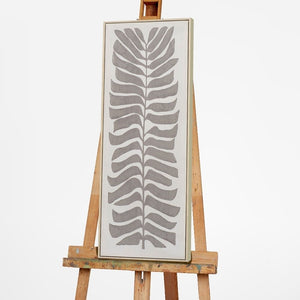 Auf einer Staffelei steht ein Bild mit dunklen Blättern. Das Gemälde hat einen schmalen Rahmen.