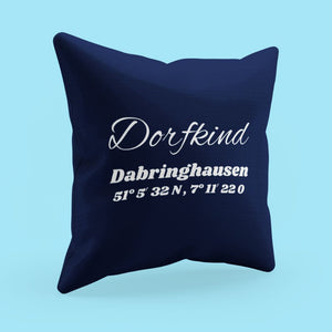 Ein blaues Kissen welches mit dem Namen Dorfkind Dabringhausen und die Koordinaten der Ortsmitte bestickt ist.