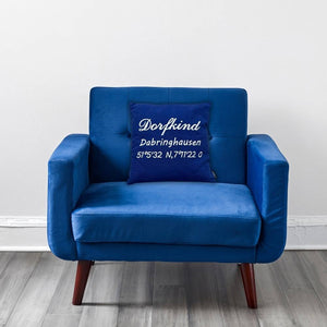 Ein blaues besticktes Kissen in einem blauen Sessel. Auf dem Kissen wurde Dorfkind Dabringhausen und die Koordinaten eingestickt.