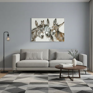 Ein modernes Wohnzimmer mit einem hellgrauen Sofa vor einer grauen Wand, über dem ein großes Querformat-Gemälde mit drei detaillierten Esel-Porträts hängt. Im Vordergrund stehen ein runder Holztisch und eine schwarze Stehlampe auf einem geometrisch gemusterten Teppich.