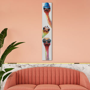 Schmales Leinwandbild hängt über einem Sofa. Auf dem Gemälde sieht man drei lustige Strausse in schillernden Farben.