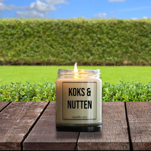 Auf einem Gartentisch steht eine Duftkerze im Glas mit der Aufschrift: Koks und Nutten.
