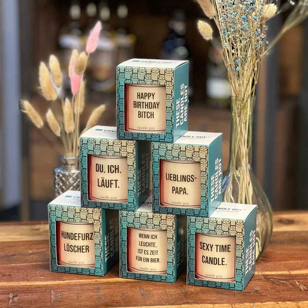 Geschenkkarton von Duftkerzen der Marke Candle Guy. Der türkise Karton hat ein Fenster um die Kerze mit dem Spruch zu sehen.