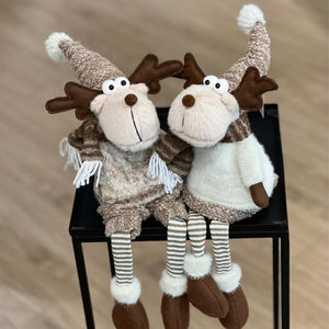 Ein niedliches Elchpaar sitzt in Wintermode gekleidet auf einem kleinen Tisch. Diese Kantenhocker von Gilde Sven und Svenja sind flauschig weich und wunderschön anzusehen.