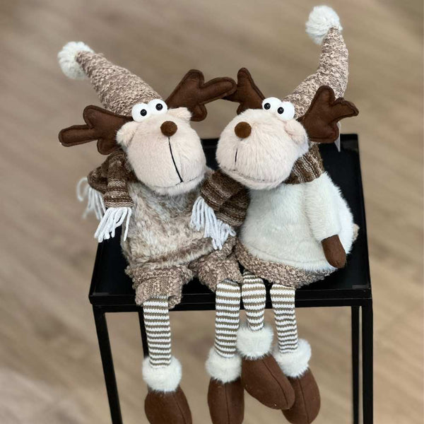 Ein niedliches Elchpaar sitzt in Wintermode gekleidet auf einem kleinen Tisch. Diese Kantenhocker von Gilde Sven und Svenja sind flauschig weich und wunderschön anzusehen.
