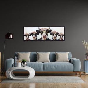 Modernes Panorama-Wandbild mit fünf lustigen Kühen, Sonnenbrillen und Perücken über einem hellblauen Sofa vor einer dunkelgrauen Wand – humorvolle Kunst für die Wohnzimmer-Deko.
