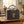 Auf dem Tisch steht ein grauer Filzshopper mit einer eingestickten Kuh mit Kopfschmuck. Im Filzshopper befindet sich Wolle. Die Filztasche ist ein idealer Aufbewahrungsort für Wolle.