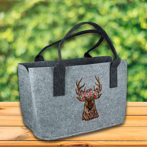 Hellgrauer Filzshopper mit einem Hirschkopf der im Geweih Blumen trägt. Der Filzshopper hat lange Henkel damit man ihn bequem schultern kann