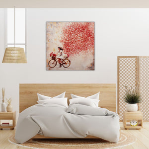 Ein Schlafzimmer mit einem Bett aus Buchenholz. An der weißen Wand hängt das Gemälde Flowers in the Air. Es zeigt eine rote Blumenwolke und davor fährt ein junges Mädchen mit einem Fahrrad und einem Blumenkorb der voll mit weißen und roten Rosen ist.