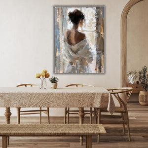 In einem Esszimmer in der Farbe Sand und creme hängt über dem Tisch ein handgemaltes Acrylgemälde von einer jungen Frau. Die Frau hat hochgesteckte braune Haare und trägt einen leichten weißen Bademantel der ihr von der Schulter rutscht. Die Frau schaut relaxed durch ein Fenster nach draußen.