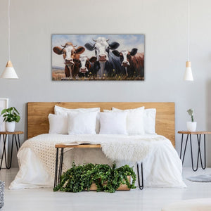 Ein Hotelzimmer mit einem Bett im Landhaus Stil. Darüber hängt ein Bild im Querformat mit zwei Kühen und zwei Kälbchen.