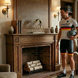 Ein Rennradfahrer mit einem Trikot aus Düsseldorf steht neben einem Kamin. Auf dem Kaminsims steht eine Statue oder Dekofigur. Es ist ein Rennrad mit einem Rennradfahrer darauf. Es ist ein Pokal oder eine Skulptur für Radfahrer.