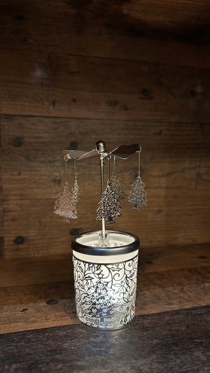 Wunderschönes Windlicht mit einem Karusell an dem Weihnachtsbäume hängen. das Teelicht ist mit satiniertem Glas zeigt einen Tannenbaum und silbernen Ornamente.