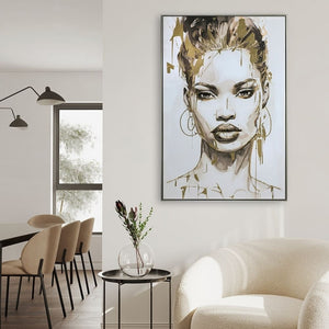 Modernes Wohn- und Esszimmer-Ambiente mit dem gerahmten XXL Frauenporträt-Gemälde „Gold covered Beauty“ an einer weißen Wand. Das Schwarz-Weiß-Kunstwerk mit Blattgold-Akzenten hängt über einem runden Beistelltisch mit Vase. Im Vordergrund steht ein Bouclé-Sessel, im Hintergrund ist ein Esstisch mit beigen Polsterstühlen zu sehen.