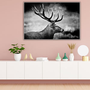 Das schwarz-weiße Hirsch-Motiv im Querformat bildet einen modernen Kontrast an einer pastell-rosa Wand, dekoriert mit Vasen, Deko-Vögeln und einer runden Design-Lampe auf einer weißen Kommode.