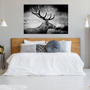 In einem Schlafzimmer im Landhausstil hängt an der wand ein gerahmter Kunstdruck in schwarz weiß. Ein stolzer Hirsch schreitet im Nebel durch sein Revier.