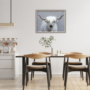 In einem Esszimmer aus hellem Holz hängt an der Wand ein Bild von einem weißen schottischen Hochlandrind. Das Fluffy Longhorn hat weißes Kunstfell am Kopf.