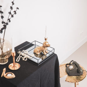 Eine Deko Figur Dackel als kerzenständer in der farbe Gold sitzt auf einem Sideboard