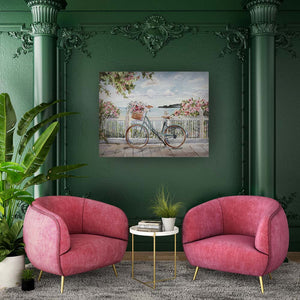 An einer grünen Wand hängt eine Gemälde mit einem Fahrrad welches einen Blumenkorb hat. Rechts und links vom Fahrrad sind Büsche mit rosafarbenen Blüten und im Hintergrund sehe ich das Meer.