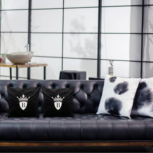 Eine schwarze Ledergarnitur mit zwei schwarzen Kissen und dem silbernen BRIDEMAKER Logo.