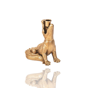 Ein goldenes Krokodil hat im Maul einen Kerzenhalter für eine Stabkerze