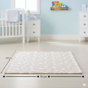 Die Kuscheldecke in der Farbe Beige hat kleine Wölkchen. Die weiche Decke für Babys liegt in einem Kinderzimmer vor einem Kinderbett.
