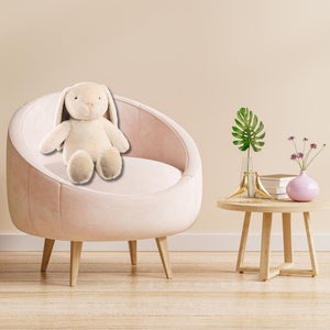 Auf einem rosafarbenen Sessel sitzt der Hase Nelly. Im Hasen ist eine flauschige Kuscheldecke versteckt.