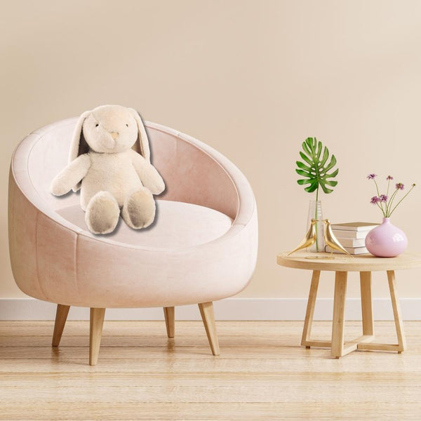 Auf einem rosafarbenen Sessel sitzt der Hase Nelly. Im Hasen ist eine flauschige Kuscheldecke versteckt.