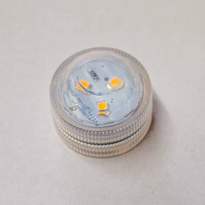 Ein kleines, zylindrisches LED-Licht mit einem klaren, strukturierten Sockel und einer transluzenten, kuppelförmigen Oberseite. Ideal um ein Windlicht zum leuchten zu bringen.