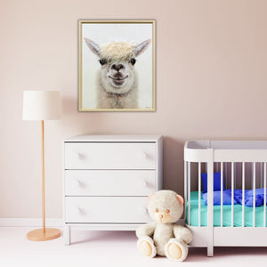 Über einem Kinderbett in einem Kinderzimmer hängt ein Bild an der rosafarbenen Wand. das Bild zeigt ein Lama mit Kulleraugen und einer wuscheligen Mähne aus Kunstfell.