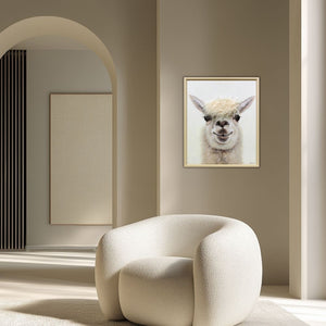 Ein modernes Wohnzimmer mit hellen Naturtönen. Ein Sessel in der Farbe beige. An der Wand hängt eine gerahmtes Bild von einem Alpaka.