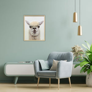 Eine mintfarbene Wand und davor steht ein bequemer Sessel vor einem Sideboard. An der wand hängt ein Bild mit einem Naturholzrahmen. Das Bild zeigt zeigt den Lama Youngster mit einer lustigen Mähne aus Kunsthaar.