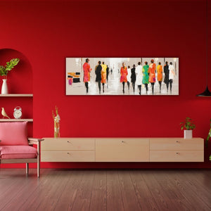 Abstraktes Panorama-Wandbild mit einer bunten Modenschau-Szene in einem modern eingerichteten Wohnzimmer. Farbintensives Kunstwerk aufgehängt an einer roten Wand über einer hellen Kommode.