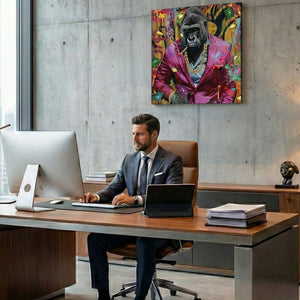 In einem modernen Büro sitzt ein Teamleader im Anzug und schaut in den Bildschirm seines PC´s. Hinter ihm hängt ein Gemälde von einem Gorilla in einem pinkfarbenen Anzug