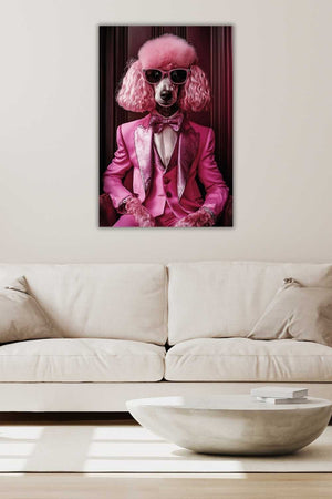 An einer beigen Wand hängt ein Glasbild von einem Pudel in der Farbe Pink. Er trägt einen pinken Anzug und eine rosa Sonnenbrille. Der Pudel sitzt auf einem Sesel vor einem dunklen Vorhang.
