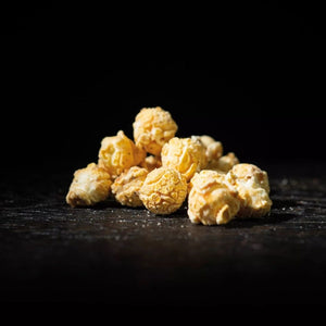 Auf einem schwarzen Tisch liegt Mushroom Popcorn Alles isst Käse von Pottkorn